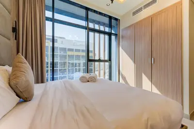 a bedroom with a large bed with two towels on it at Chic 1 Bed Oasis in Azizi Riviera in Dubai