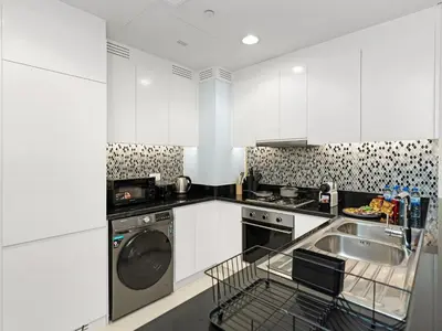a white kitchen with a dishwasher and a sink at WonderfulStay at Paramount Residences - Highest Infinity Pool - Burj Khalifa View - Brand New Luxury Apartments in Dubai