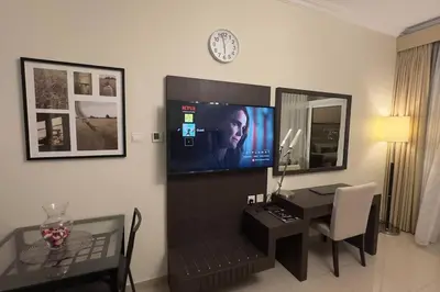 a living room with a desk and a clock on the wall at Stylish Studio With Amazing View in Dubai