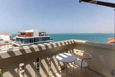 a balcony with a table and chairs and the ocean at Palm Jumeirah Sea View 1Bdr in Dubai