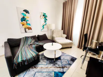 a living room with a couch and a table at Elegant Fresh 1BR with Heated Pool, just steps from Mall, Restaurants & Fitness center in Dubai