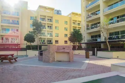 a large apartment building with a brick fireplace in a courtyard at Frank Porter - Al Dhafrah 2 in Dubai