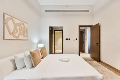 a white bedroom with a large white bed with pillows at Modern 2 BR Apartment near Dubai Butterfly Garden in Dubai