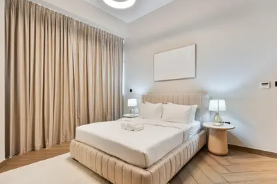 a bedroom with a large white bed with curtains at Modern 2 BR Apartment near Dubai Butterfly Garden in Dubai