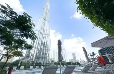 a pool with chairs and an umbrella and a tall building at FAM Living - Address Residences Opera - Luxurious 2Bed in Dubai