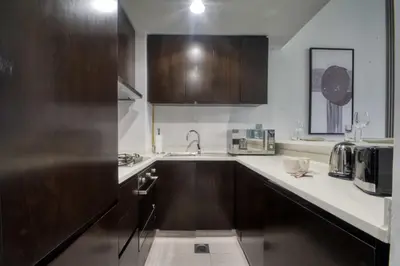 a kitchen with wooden cabinets and a counter top at 1-Bedroom in Merano Tower, Business Bay with City Views in Dubai
