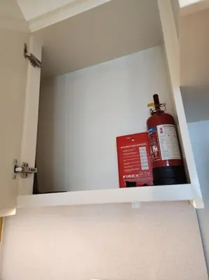 a cabinet with a fire extinguisher and a bottle in it at Your Dubai Home in Dubai