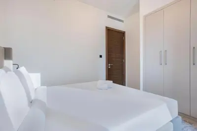 a white bedroom with a white bed and a door at STAY BY LATINEM Luxury 1BR Holiday Home CVR B2303 near Burj Khalifa in Dubai