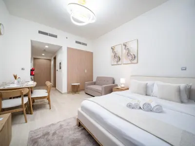 a bedroom with a large white bed and a dining room at Chic Studio Azizi Riviera Retreat with City Views in Dubai