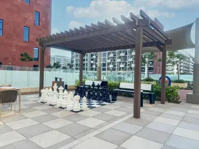 a chess set on a patio with a wooden canopy at Chic Studio Azizi Riviera Retreat with City Views in Dubai