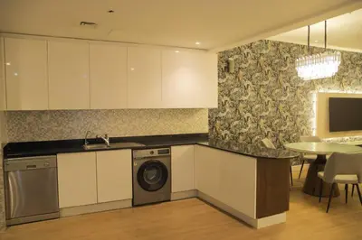 a kitchen with white cabinets and a washer and a table at Stunning SeaView Elite Residence Dubai Marina in Dubai