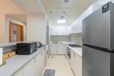 a kitchen with white cabinets and a stainless steel refrigerator at Elegant 1BR Apartment in Dubai LuxuryStay in Dubai