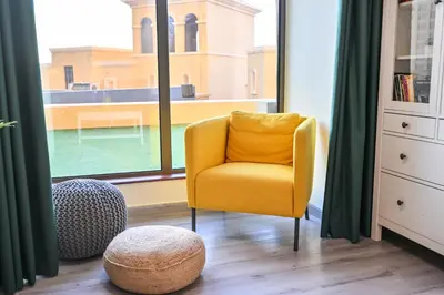 a yellow chair in a room with a large window at 7 Beds - JBR Beach 3 min walk in Dubai