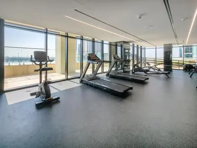 a gym with treadmills and machines in a room with windows at Wonderful New Studio in Missoni Business Bay in Dubai