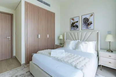 a white bedroom with a large bed with white pillows at Nasma - Modern 3BR Oasis with Balcony in Azizi Riviera in Dubai