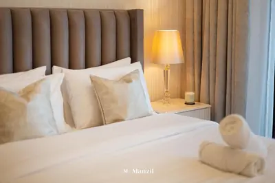 a bedroom with a bed with white pillows and a lamp at Manzil - 2BR Apartment in Palm Jumeirah with Marina View in Dubai