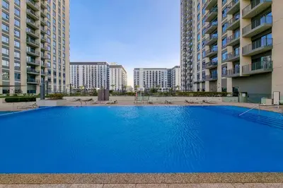 a large blue swimming pool in front of tall buildings at First class 1BR Hall in Park Heights in Dubai