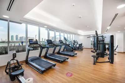 a gym with a row of treadmills and ellipticals at Elegant Studio in Bloom Towers B, JVC by Deluxe Holiday Homes in Dubai