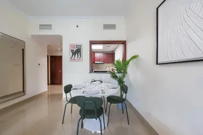 a dining room with a white table and green chairs at Perfect Stay - 1Bedroom with full Marina View in Dubai