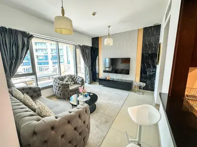 a living room with a couch and a tv at Vserve - 1 BR Spacious Majestic Burj Khalifa view in Dubai