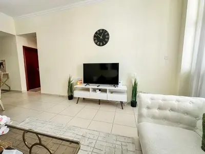 a living room with a television and a clock on the wall at Vserve - 1 BR Stunning Canal and Burj Khalifa View in Dubai