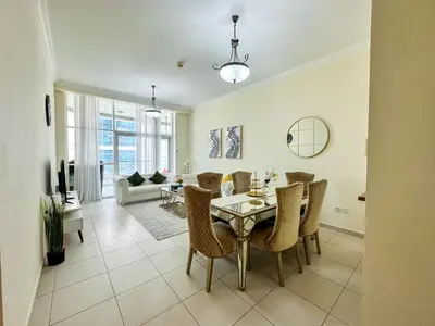 a dining room and living room with a table and chairs at Vserve - 1 BR Stunning Canal and Burj Khalifa View in Dubai