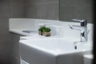 a white bathroom sink with a plant on it at Premium 1BR Haven with Burj Khalifa, City Skyline Views, Pool, Gym & Balcony in Dubai