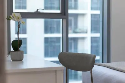 a bedroom with a chair and a desk and a window at Premium 1BR Haven with Burj Khalifa, City Skyline Views, Pool, Gym & Balcony in Dubai