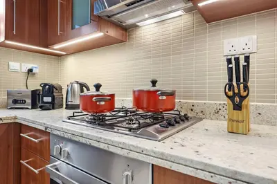 two red pots on a stove in a kitchen at Skyline Views 2BR Near Burj Khalifa & Dubai Mall with Pool Access in Dubai