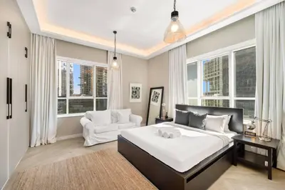 a bedroom with a bed and a couch and windows at 2BR Family Apt with Pool, Gym and Jumeirah Lake Views in Dubai