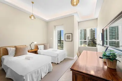 a white room with two beds and a table at 2BR Family Apt with Pool, Gym and Jumeirah Lake Views in Dubai
