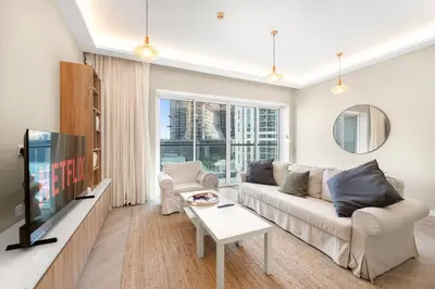a living room with a couch and a tv at 2BR Family Apt with Pool, Gym and Jumeirah Lake Views in Dubai