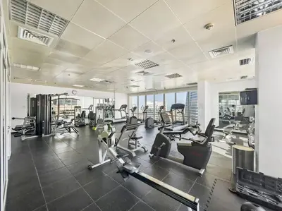 a gym with cardio equipment in a large room at 2BR Family Apt with Pool, Gym and Jumeirah Lake Views in Dubai