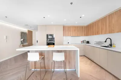a kitchen with a white counter and two bar stools at 2BR Family Apt with Pool, Gym and Jumeirah Lake Views in Dubai
