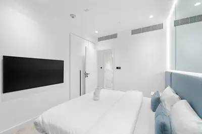 a white bedroom with a large bed and a flat screen tv at FIRST CLASS Dubai Marina 2BR with City Views, Balcony, Pool, Gym & Parking in Dubai