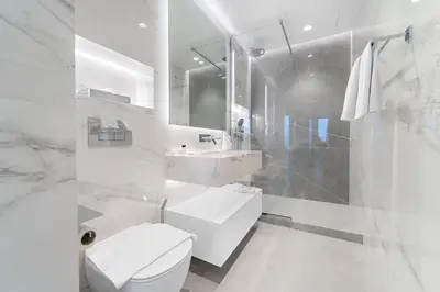 a white bathroom with a toilet and a sink at FIRST CLASS Dubai Marina 2BR with City Views, Balcony, Pool, Gym & Parking in Dubai
