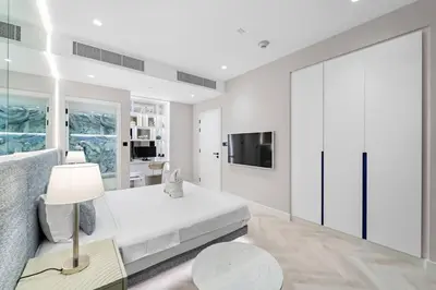 a white bedroom with a bed and a tv at FIRST CLASS Dubai Marina 2BR with City Views, Balcony, Pool, Gym & Parking in Dubai