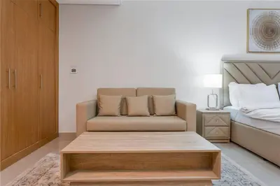 a living room with a couch and a bed at Chic Studio Stay with Gym, Pool, and Kitchenette in Dubai