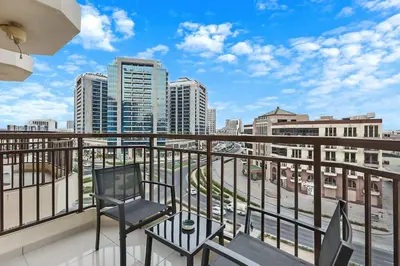 a balcony with two chairs and a view of a city at Chic Studio Stay with Gym, Pool, and Kitchenette in Dubai