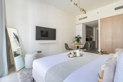 a white bedroom with a bed and a table at Frank Porter - Azizi Riviera 28 in Dubai