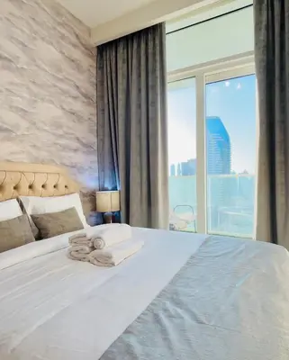 a bedroom with a white bed with a large window at Modern Apartment in Downtown Dubai in Dubai