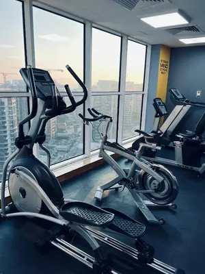 a gym with three exercise bikes in a room with windows at Modern 1BR Unit with Canal View Near Burj Khalifa in Dubai