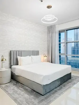 a white bedroom with a large bed and a window at Burj Khalifa View Apartment 10 min Walking to Dubai Mall in Dubai