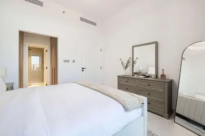 a white bedroom with a bed and a mirror at Legacy by Sunrise - Top Amenities and Paddle Court in Dubai