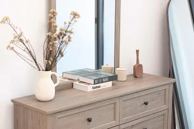 a wooden dresser with books and a mirror at Legacy by Sunrise - Top Amenities and Paddle Court in Dubai