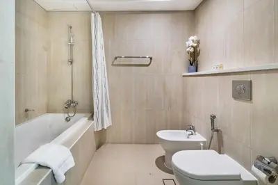 a bathroom with a toilet and a tub and a sink at Beachy Getaway in JBR with Private Beach Access in Dubai