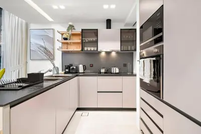 a kitchen with white cabinets and black counter tops at FIRST CLASS 3BR Lively Sanctuary in Dubai