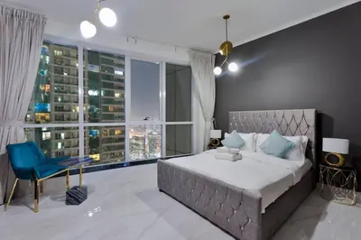 a bedroom with a large bed and a blue chair at Luxury 2BRin Torch Tower with Dubai Marina Skyline Views in Dubai