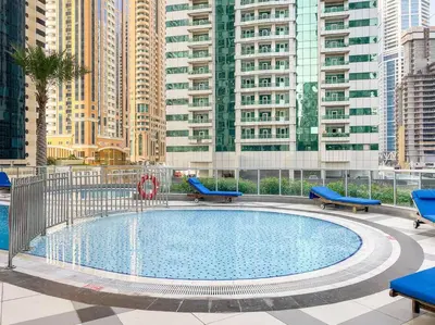 a swimming pool with blue chairs and buildings at Luxury 2BRin Torch Tower with Dubai Marina Skyline Views in Dubai