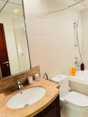 a bathroom with a sink and a toilet and a mirror at 1 BHK Apartment in Dubai in front of Burj Khalifa in Dubai